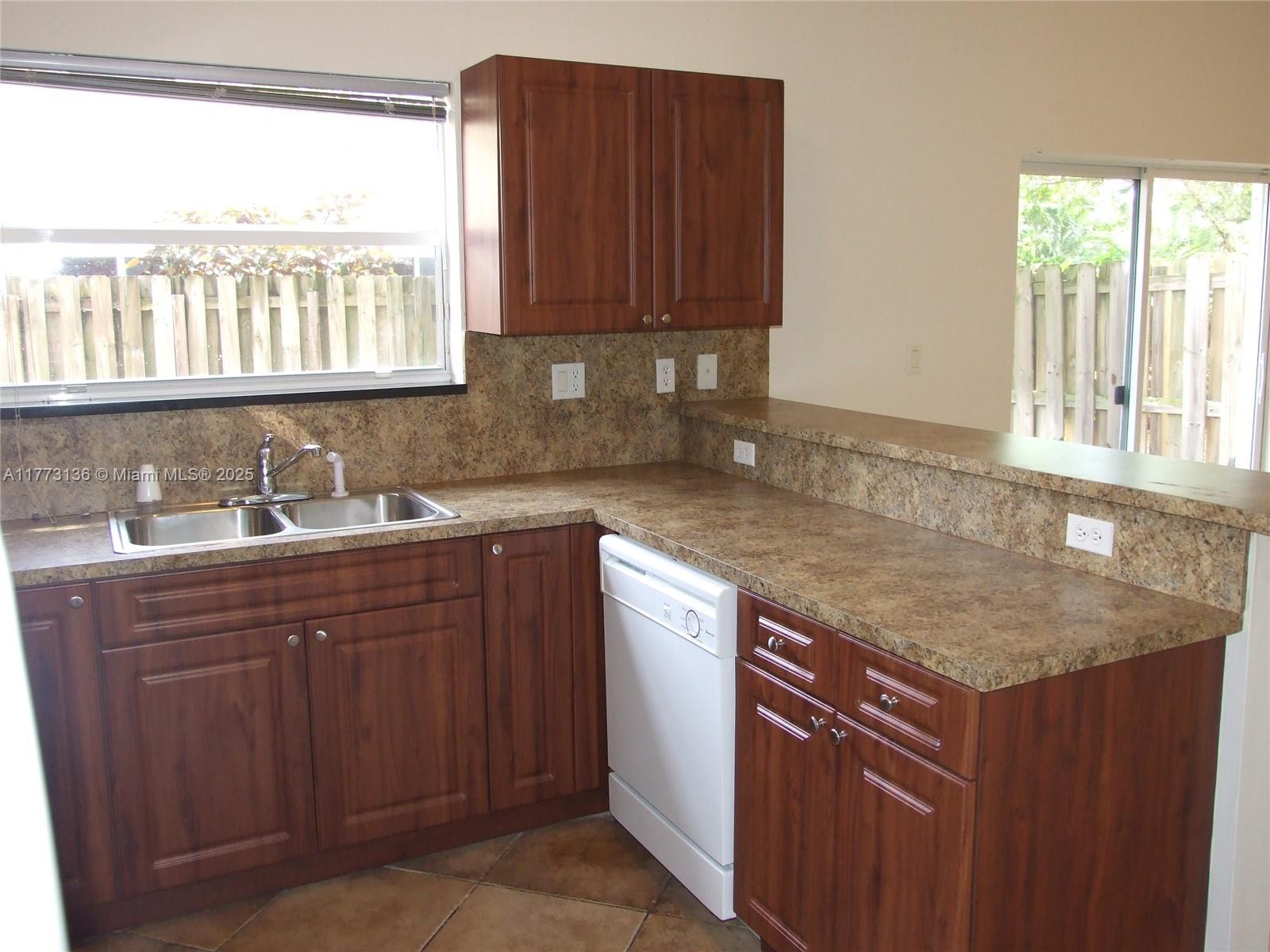 A kitchen features wood cabinets, laminate countertops, a double sink, and a white dishwasher — 14082 SW 50th Ct, Miramar FL 33027, MIRAMAR, FL