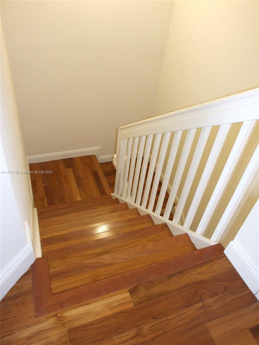 A wooden staircase with white railings leads down to a landing — 14082 SW 50th Ct, Miramar FL 33027, MIRAMAR, FL