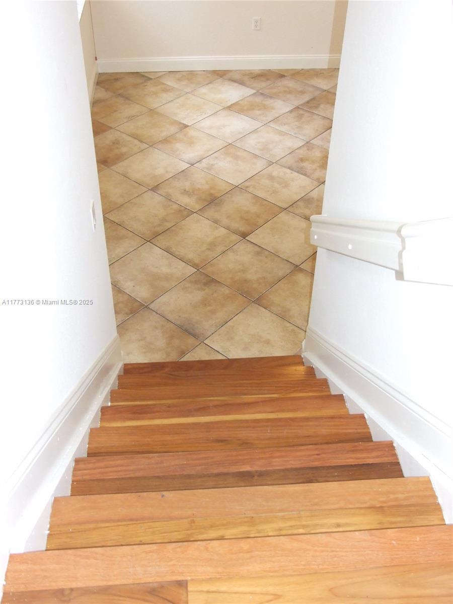 A wooden staircase leads down to a room with diagonal tan floor tiles — 14082 SW 50th Ct, Miramar FL 33027, MIRAMAR, FL