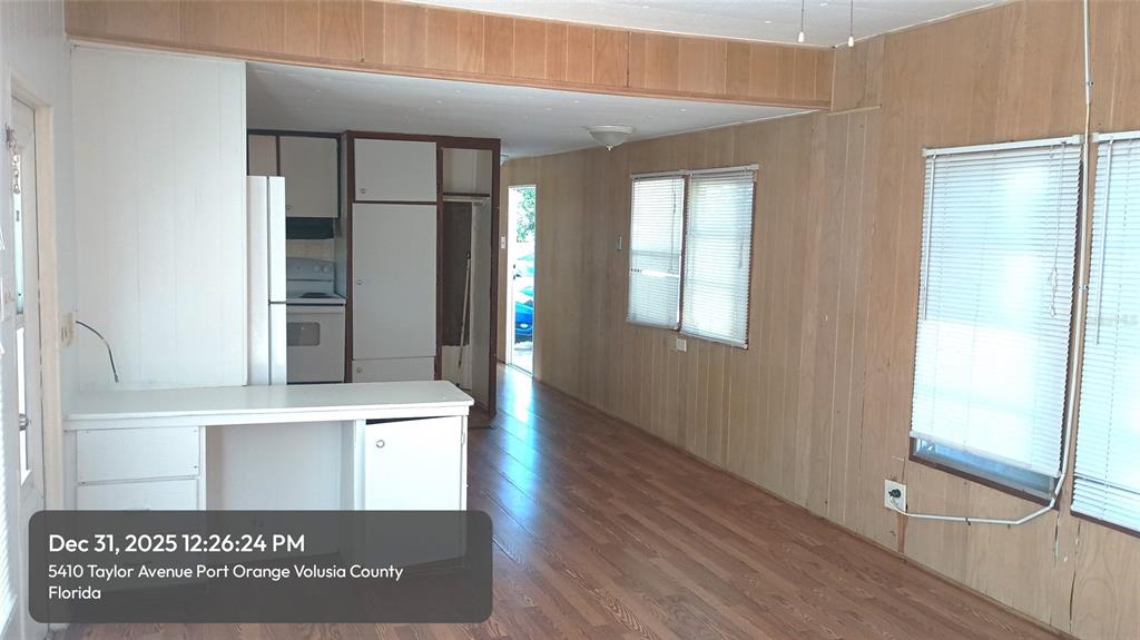 An interior view shows a kitchen with white cabinets and wood-paneled walls — 5410 TAYLOR AVENUE, PORT ORANGE, FL