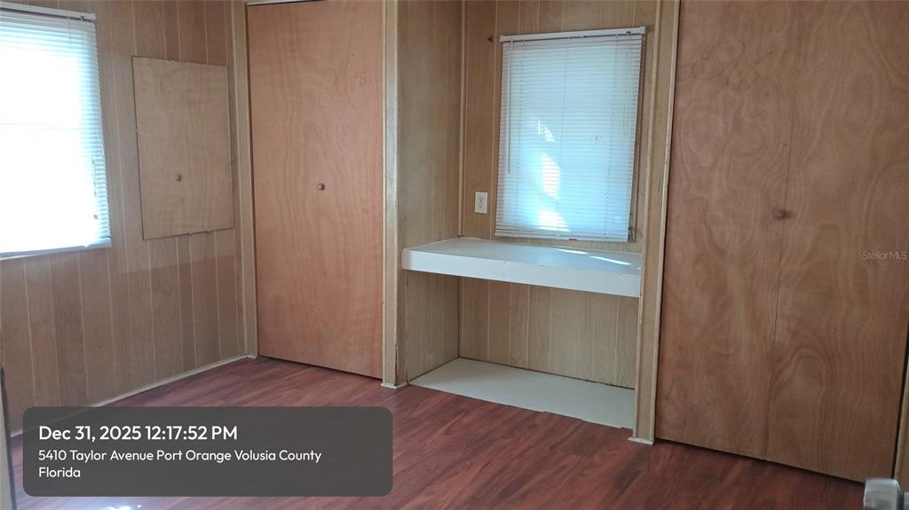 A room with wood-paneled walls, wood-look flooring, two windows with blinds, and a built-in desk — 5410 TAYLOR AVENUE, PORT ORANGE, FL