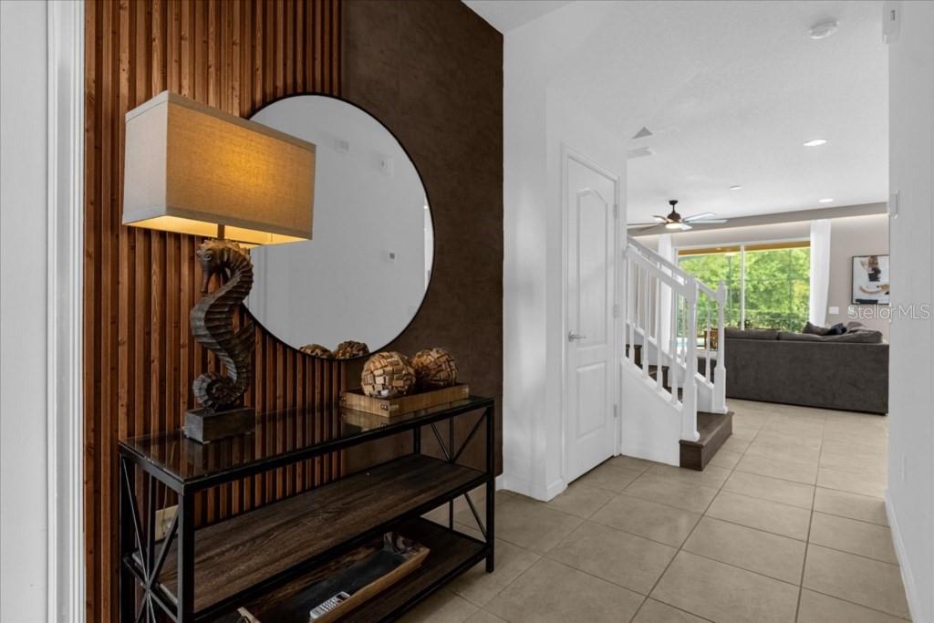An entryway features a wood-slat accent wall, a round mirror, and a console table — 5220 OAKBOURNE AVENUE, DAVENPORT, FL