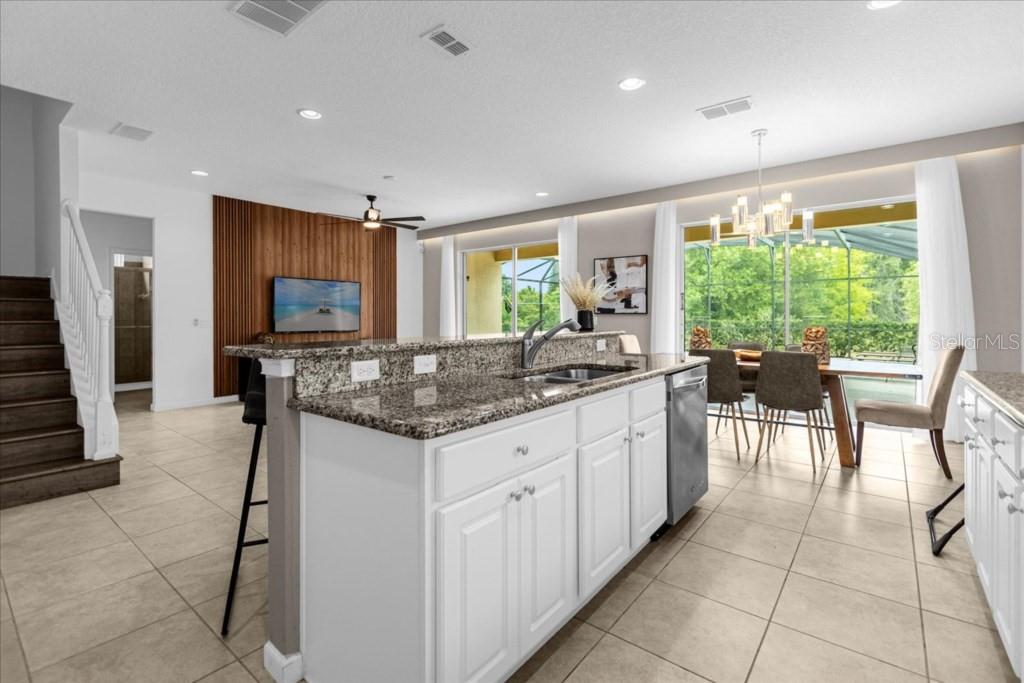 A kitchen island with granite countertops overlooks a dining area and a living room — 5220 OAKBOURNE AVENUE, DAVENPORT, FL
