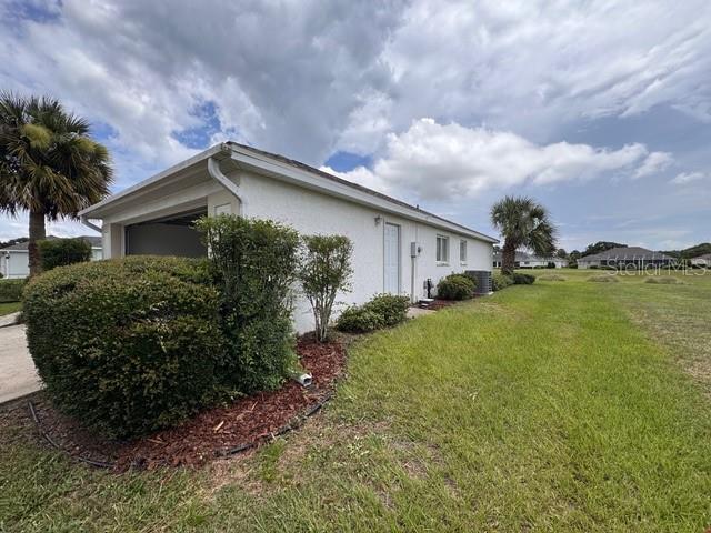 A side view of a white stucco house with a garage and a large bush — 5126 NW 26TH STREET, OCALA, FL