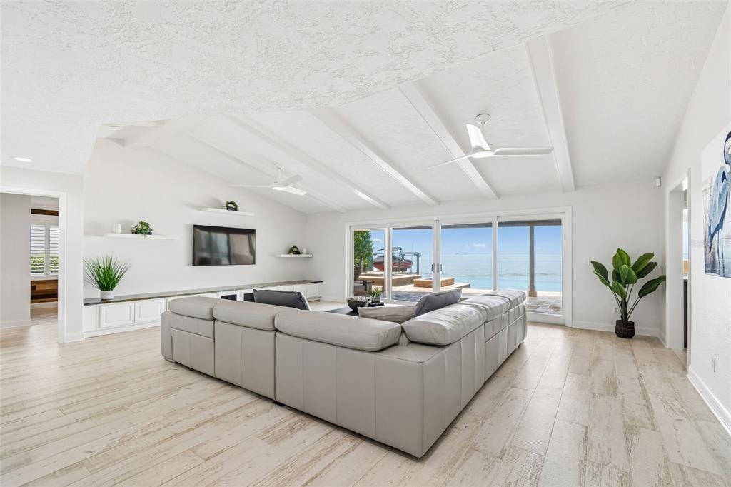 A bright living room features a large sectional sofa, vaulted ceilings, and sliding glass doors — 2038 CAROLINA AVENUE NE, ST PETERSBURG, FL