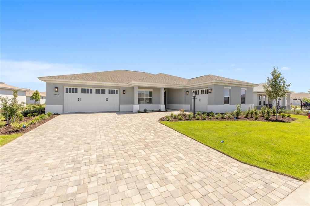 A single-story house with a paved driveway, two-car garage, and light gray exterior siding — 10252 SW 85TH PLACE ROAD, OCALA, FL