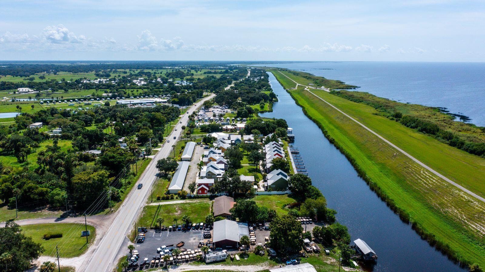 Aerial view of a waterfront property with a canal, road, and surrounding residential buildings — 4334 U.s. 441 # 24, Okeechobee FL 34974, OKEECHOBEE, FL