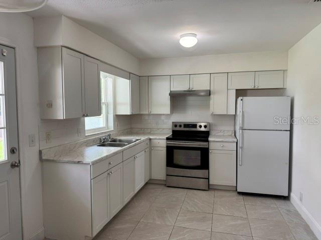 A kitchen features white cabinets, light countertops, stainless steel appliances, and tile flooring — 27127 FERNERY AVENUE, BROOKSVILLE, FL