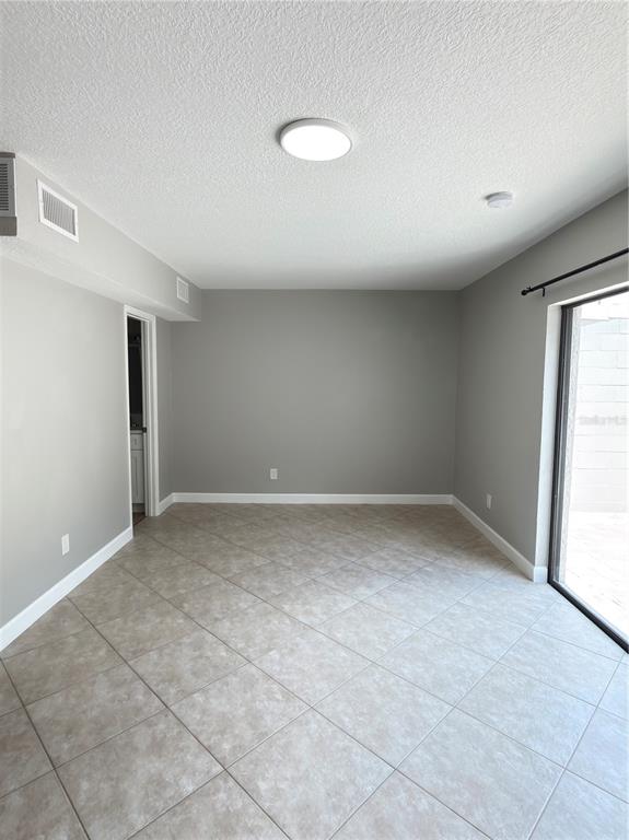 An empty room with gray walls, tile flooring, a ceiling light, and a sliding glass door — 8443 N GRADY AVENUE, TAMPA, FL