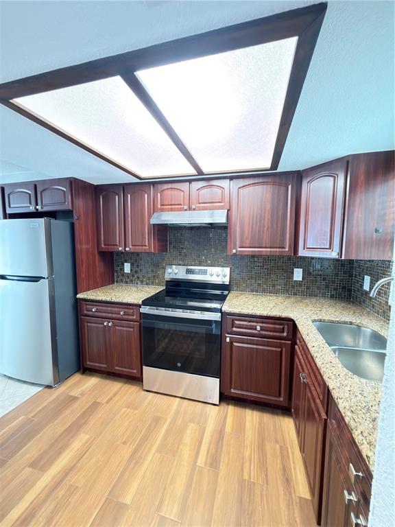 A kitchen features dark wood cabinets, granite countertops, stainless steel appliances, and a tiled backsplash — 8443 N GRADY AVENUE, TAMPA, FL