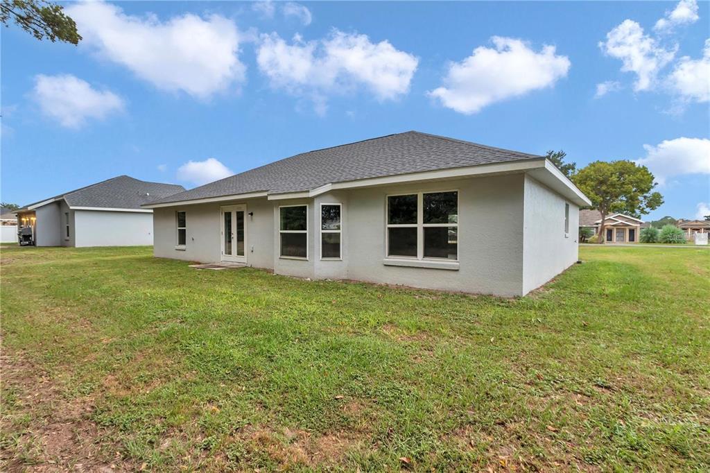 The exterior rear view of a single-story house with a gray roof and light-colored stucco — 6711 SW 64TH AVENUE, OCALA, FL