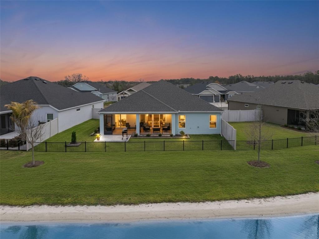 An aerial view of a single-story house with a screened patio overlooking a lake — 7492 FAR HILLS LOOP, THE VILLAGES, FL