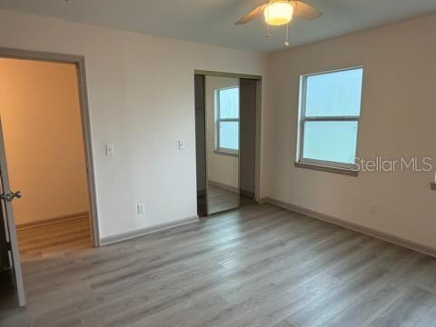A bedroom with light-colored walls, wood-look flooring, a ceiling fan, and a mirrored closet door — 4255 43RD AVENUE N, ST PETERSBURG, FL