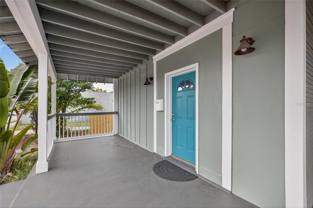 A covered front porch features a teal door, gray painted floor, and board-and-batten siding — 105 W COLUMBUS DRIVE, TAMPA, FL