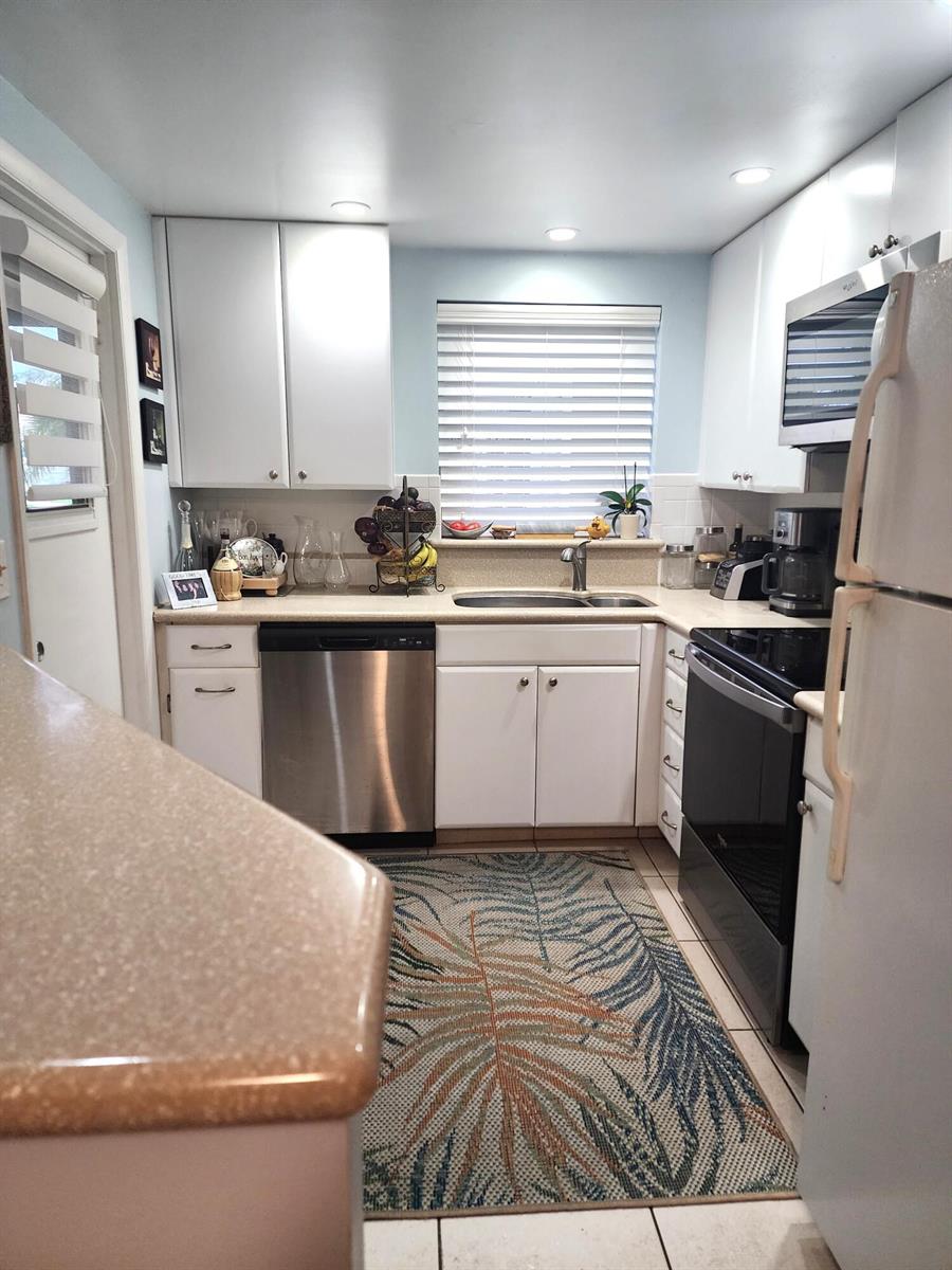 A kitchen with white cabinets, stainless steel appliances, a patterned rug, and light-colored countertops — 804 SE 7th Street # 101, Deerfield Beach FL 33441, DEERFIELD BEACH, FL