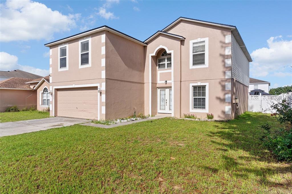 A two-story tan stucco house with white trim and a two-car garage — 257 VERVAIN AVENUE, DAVENPORT, FL