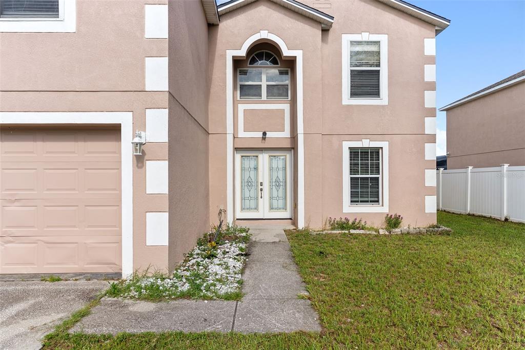 A two-story house with a tan stucco exterior, white trim, and a double front door — 257 VERVAIN AVENUE, DAVENPORT, FL