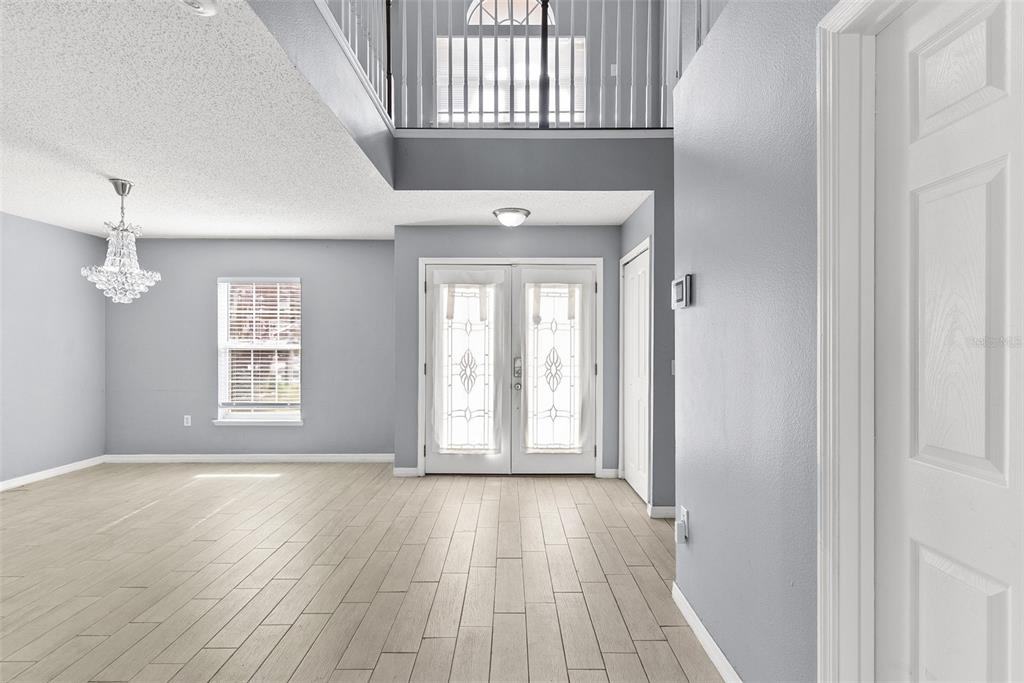 An entryway with light gray walls, wood-look tile flooring, a crystal chandelier, and double doors — 257 VERVAIN AVENUE, DAVENPORT, FL