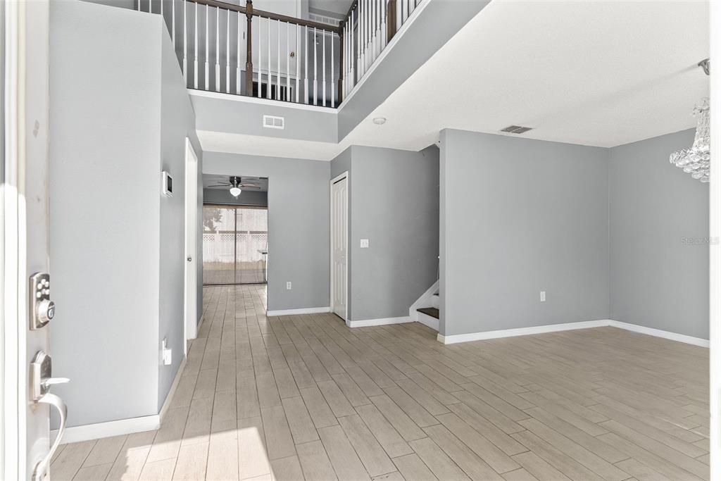 An entryway with light wood-look tile flooring leads to a two-story foyer and staircase — 257 VERVAIN AVENUE, DAVENPORT, FL