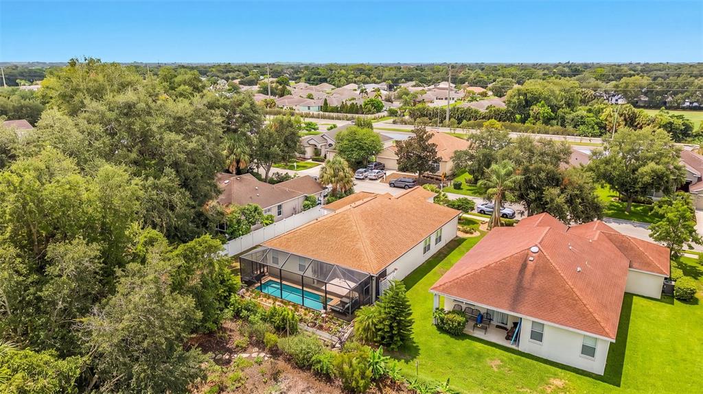 An aerial view shows two suburban houses with brown roofs, one featuring a screened-in pool — 3111 43RD AVENUE E, BRADENTON, FL