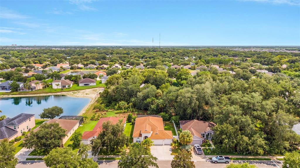 An aerial view shows a suburban neighborhood with houses, a pond, and dense trees — 3111 43RD AVENUE E, BRADENTON, FL