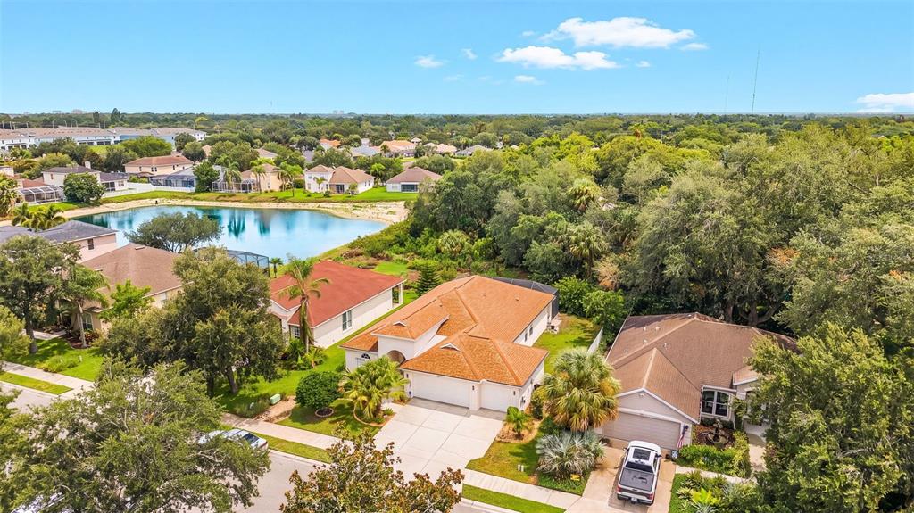 An aerial view shows suburban houses with tiled roofs near a lake and trees — 3111 43RD AVENUE E, BRADENTON, FL