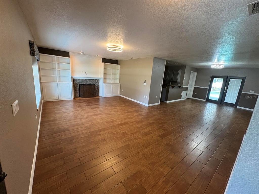 A spacious living room features wood-look tile flooring, a fireplace with built-in shelves, and French doors — 2 FT CLINCH HEIGHTS ROAD, FROSTPROOF, FL