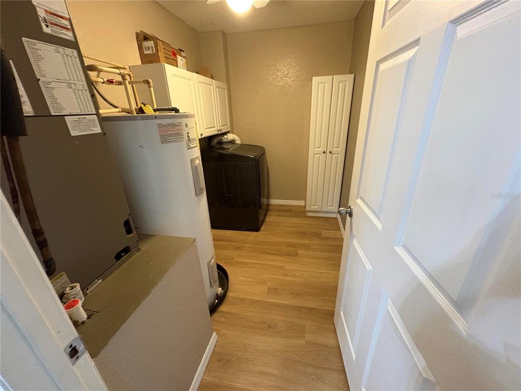 A laundry room features a water heater, furnace, black washing machine, and white storage cabinets — 2 FT CLINCH HEIGHTS ROAD, FROSTPROOF, FL