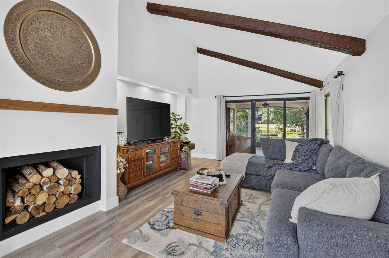 A living room features a fireplace with stacked logs, wood ceiling beams, and a sectional sofa — 5918 Patio Drive, Boca Raton FL 33433, BOCA RATON, FL