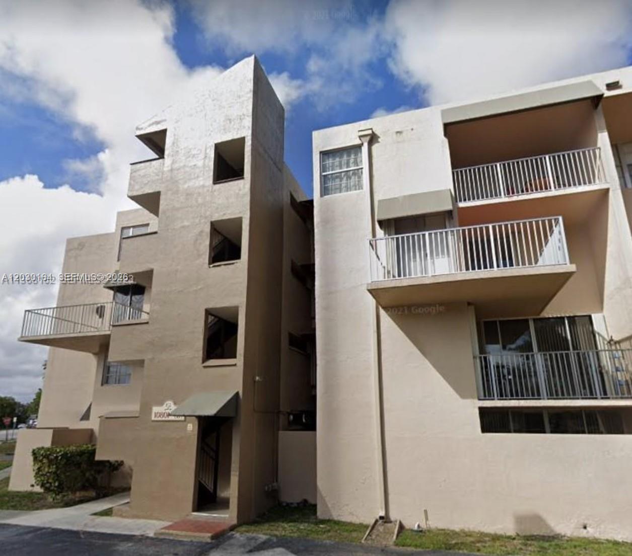 The exterior of a multi-story tan apartment building features balconies and a central stairwell — 10801 SW 109th Ct # D412, Miami FL 33176, MIAMI, FL