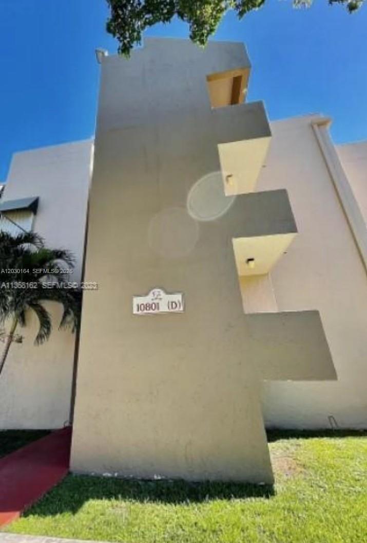 This exterior view shows a multi-story beige building with stacked balconies and a unit number plaque — 10801 SW 109th Ct # D412, Miami FL 33176, MIAMI, FL