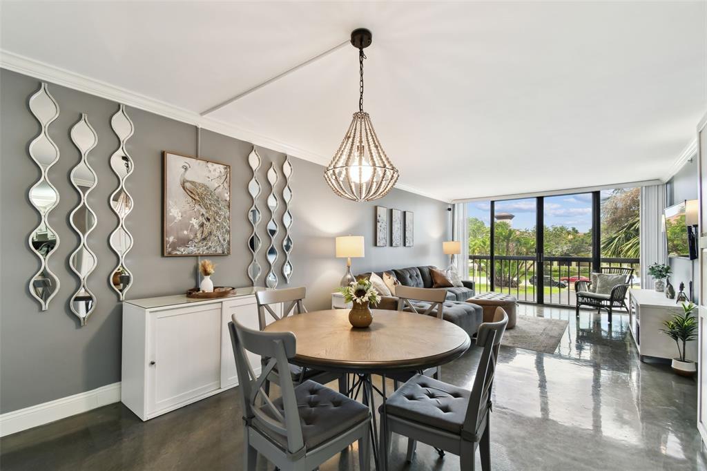 A dining area and living room with gray walls, a round table, and concrete floors — 255 DOLPHIN POINT UNIT 207, CLEARWATER BEACH, FL