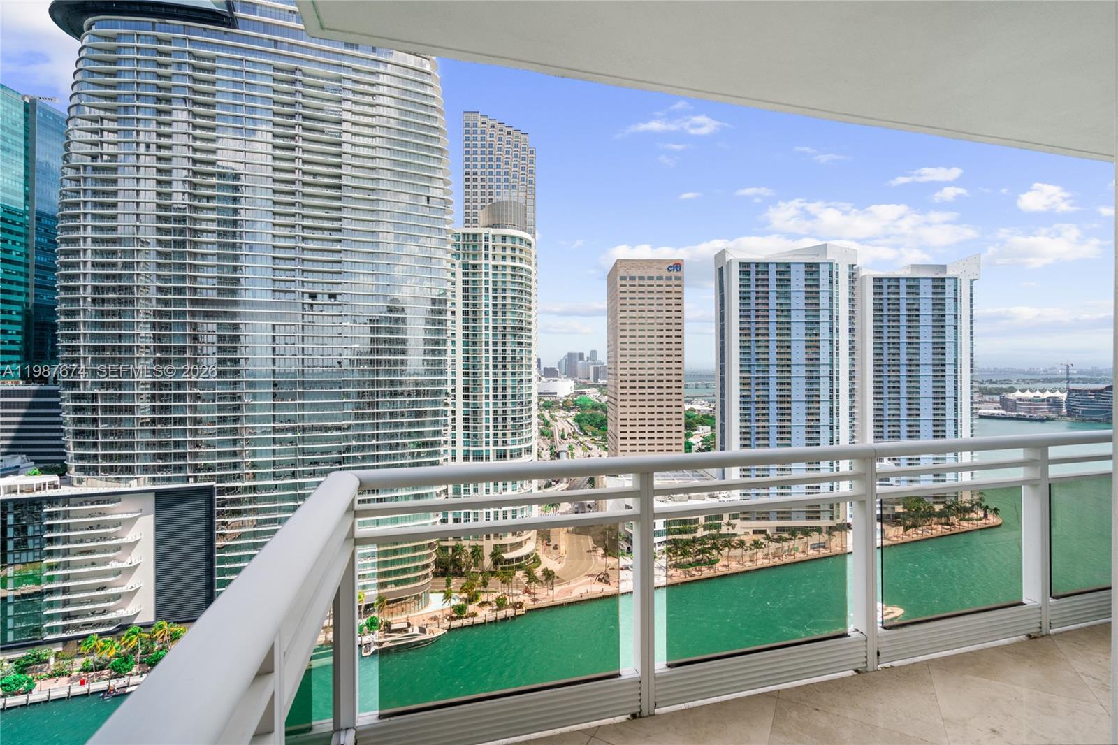 A balcony overlooks a canal and high-rise buildings in a dense urban city — 901 Brickell Key Blvd # 2804, Miami FL 33131, MIAMI, FL
