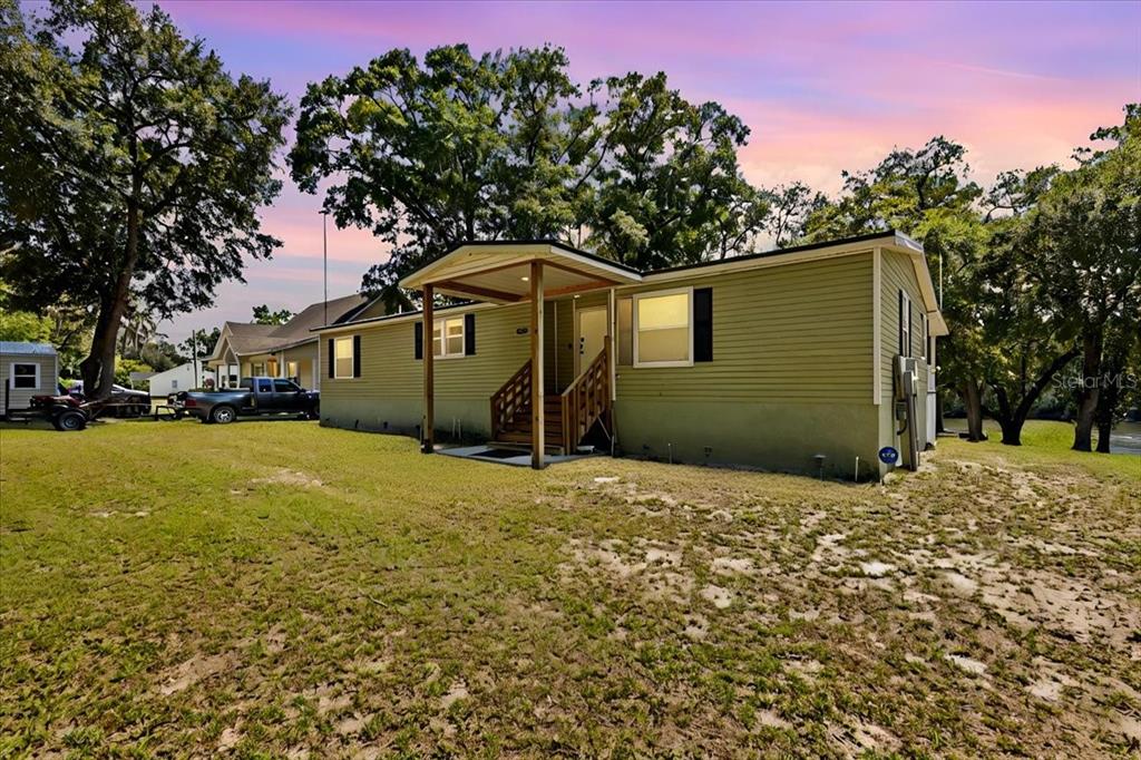 A light green single-story house with a covered front porch sits on a grassy lot — 9859 NW 38TH TERRACE, BRANFORD, FL