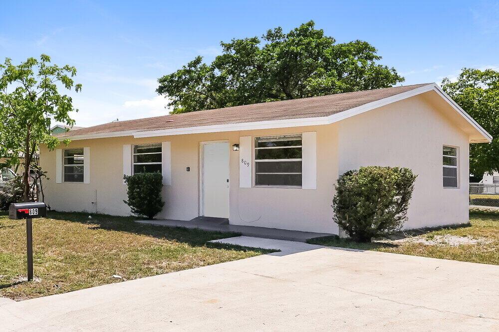 A single-story, light-colored house with a concrete driveway and a mailbox in the front yard — HALLANDALE BEACH, FL