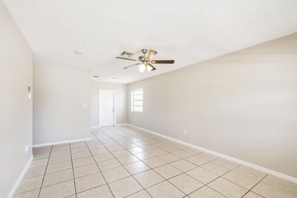 An empty room with beige walls, a ceiling fan, and light-colored tile flooring — HALLANDALE BEACH, FL