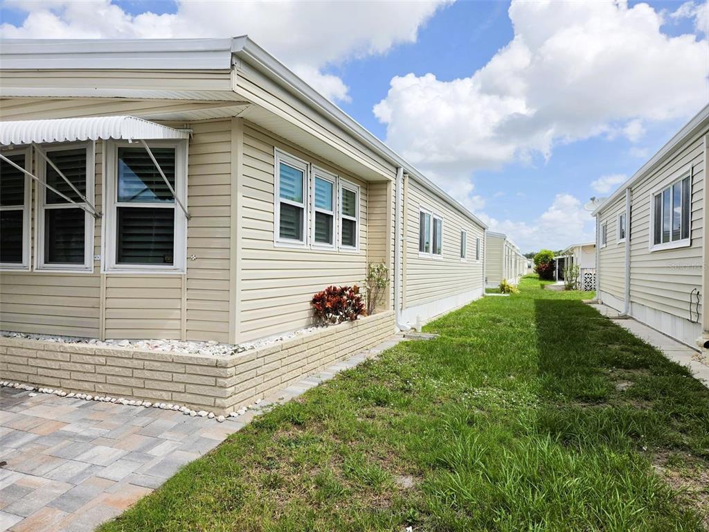 The exterior of a beige manufactured home features vinyl siding, a brick foundation, and windows — 3227 BAYBERRY TERRACE, SARASOTA, FL