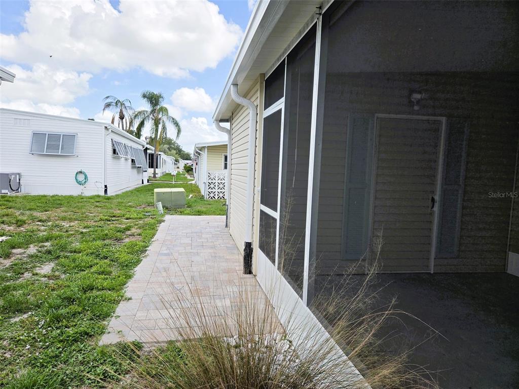 A paved walkway runs alongside a house with a screened-in porch and exterior siding — 3227 BAYBERRY TERRACE, SARASOTA, FL