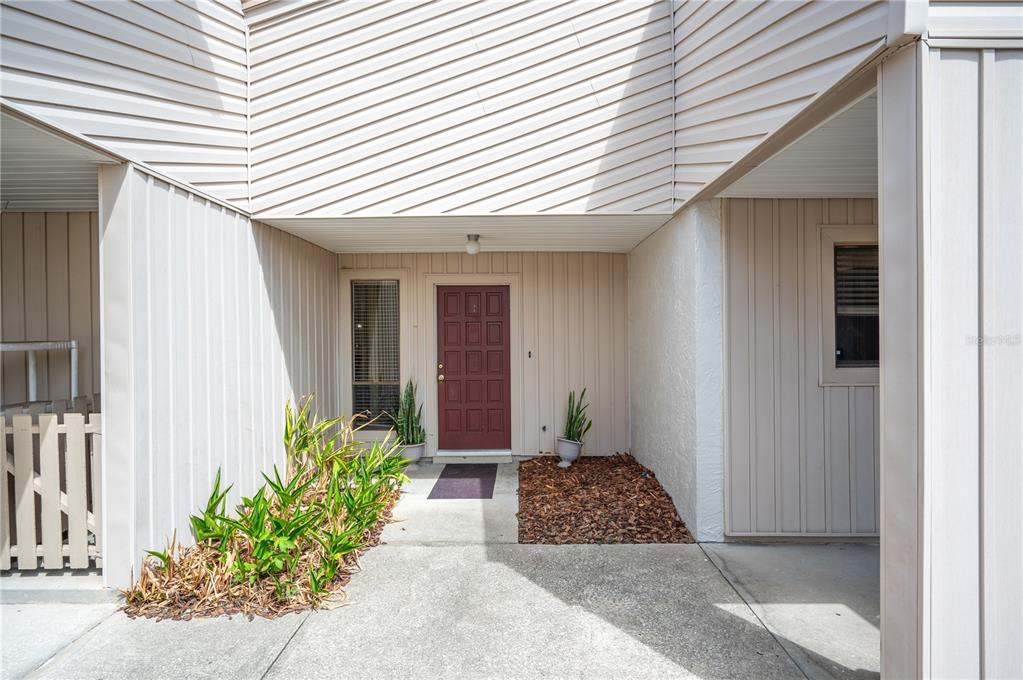 An exterior view of a home entrance with a red door and concrete walkway — 4231 OAK LOOP UNIT 51, MULBERRY, FL