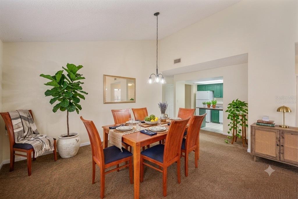 A dining room with a wooden table, six chairs, a large plant, and carpeted flooring — 4231 OAK LOOP UNIT 51, MULBERRY, FL