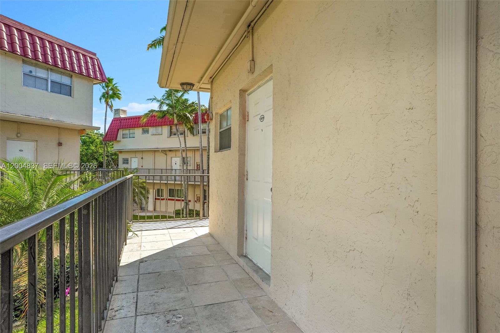 An outdoor balcony features tiled flooring, a metal railing, and a white entry door — 8650 SW 67th Ave # 1025, Pinecrest FL 33156, PINECREST, FL