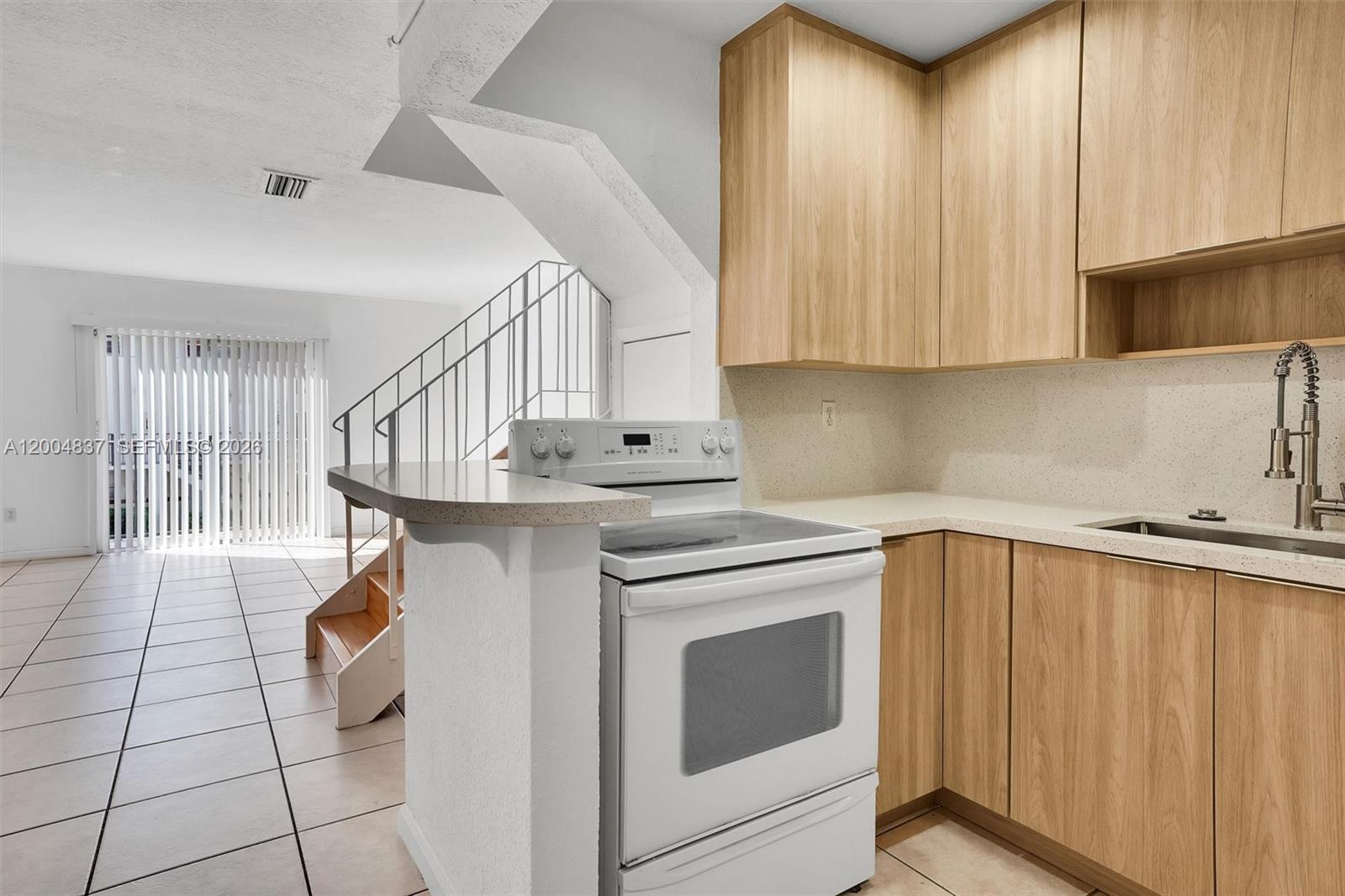 A kitchen with light wood cabinets, a white stove, and a beige countertop — 8650 SW 67th Ave # 1025, Pinecrest FL 33156, PINECREST, FL