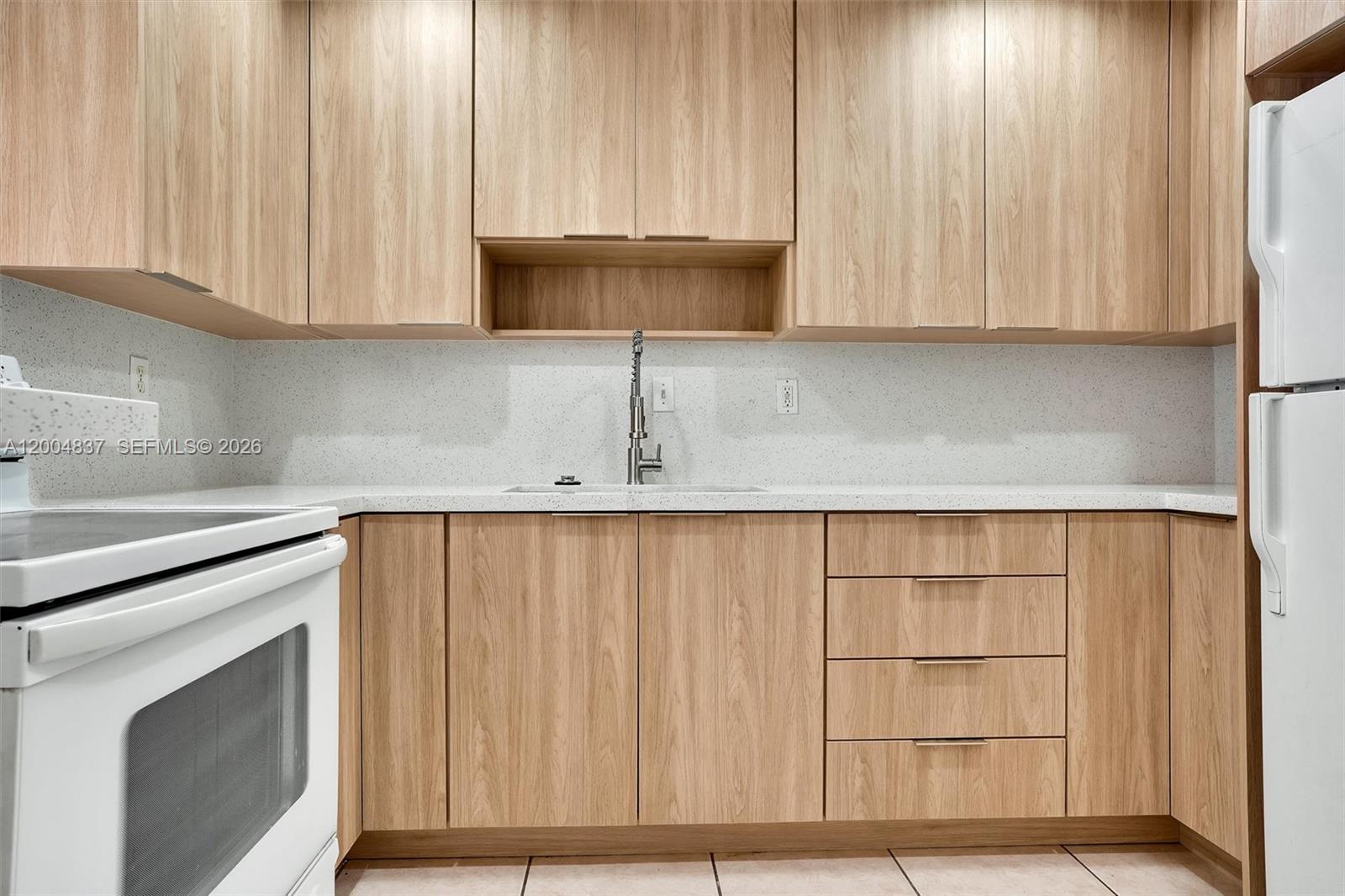 A kitchen features light wood cabinets, white countertops, and white appliances — 8650 SW 67th Ave # 1025, Pinecrest FL 33156, PINECREST, FL