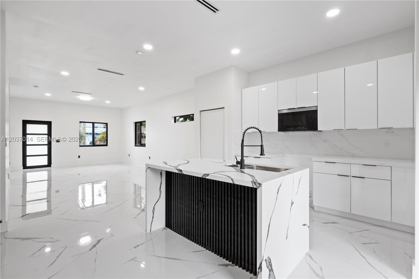 A modern kitchen features white glossy cabinets, a marble-topped island, and white tiled floors — 426 SW 9th Ave, Homestead FL 33030, HOMESTEAD, FL