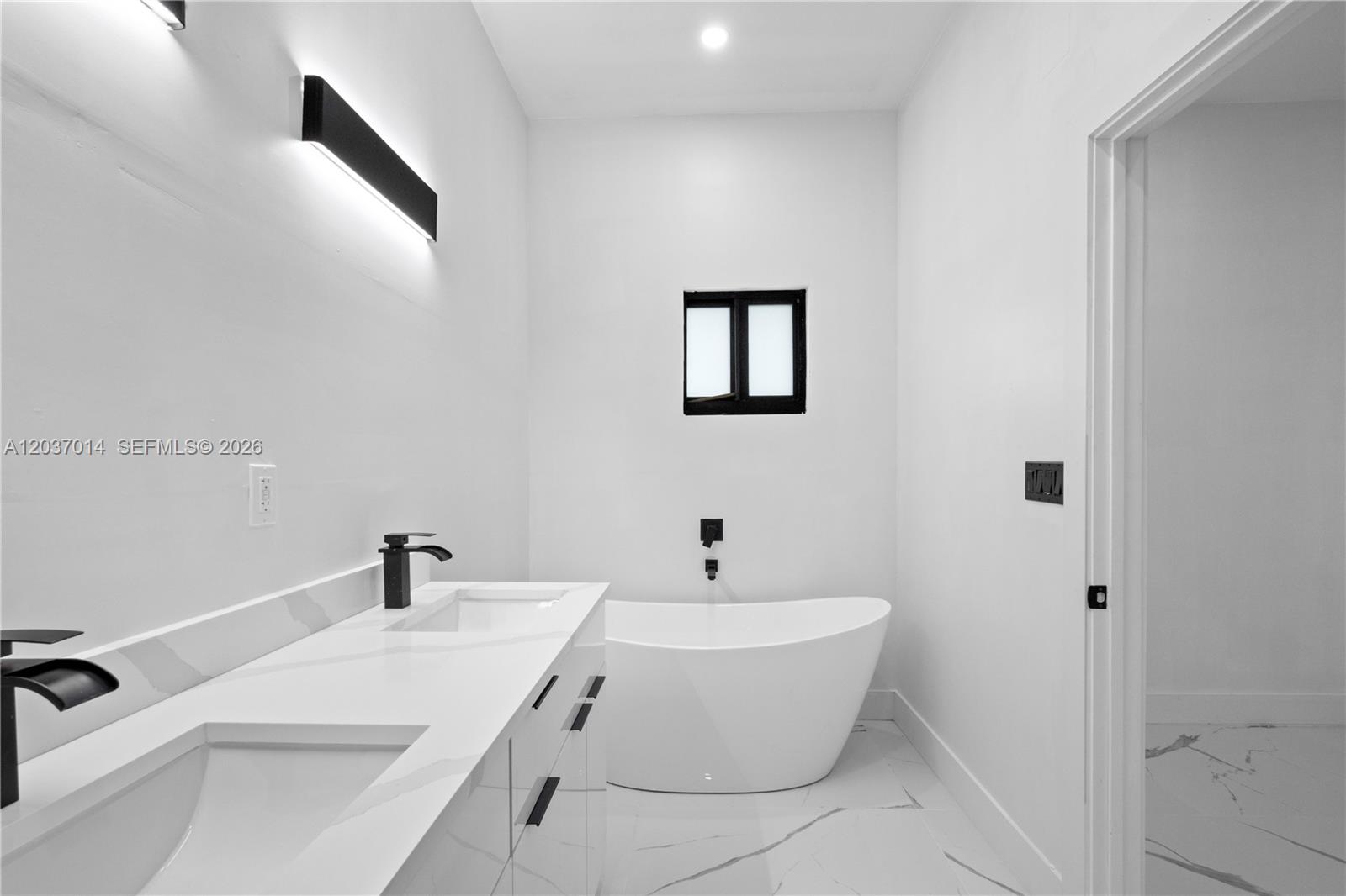 A modern bathroom features a double vanity, a freestanding soaking tub, and black fixtures — 426 SW 9th Ave, Homestead FL 33030, HOMESTEAD, FL