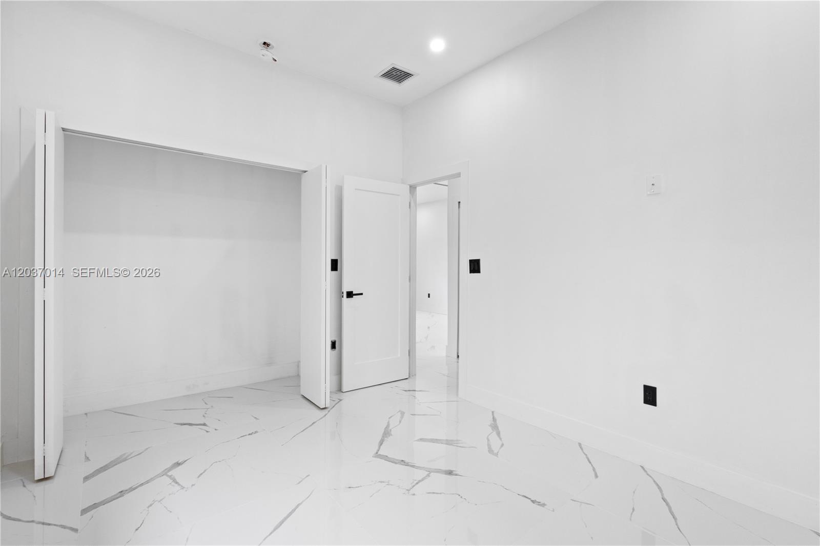 A minimalist room features white walls, marble-patterned tile flooring, a closet, and an open doorway — 426 SW 9th Ave, Homestead FL 33030, HOMESTEAD, FL