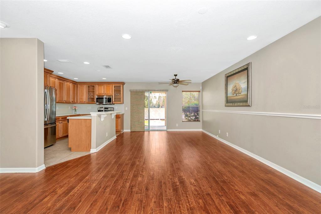 An open-concept living area with hardwood floors, a kitchen with wood cabinets, and sliding doors — 2916 ROYAL TUSCAN LANE, VALRICO, FL