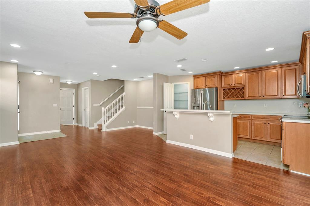 An open-concept living area with wood flooring, a ceiling fan, and a kitchen with wood cabinets — 2916 ROYAL TUSCAN LANE, VALRICO, FL