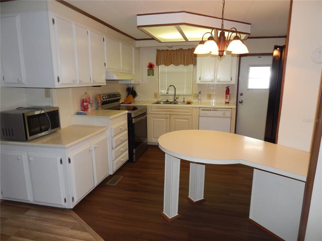 A kitchen with white cabinets, dark wood-look flooring, a peninsula, and a central light fixture — 6710 36TH AVENUE E UNIT 34, PALMETTO, FL