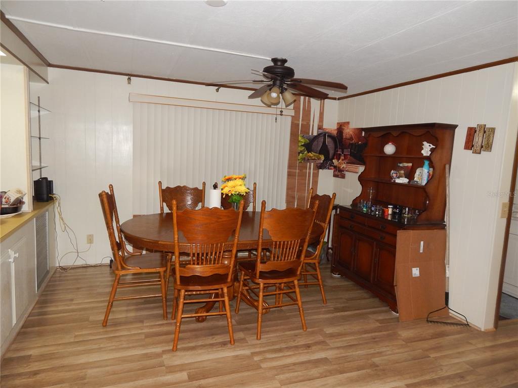 A dining room features wood-look flooring, a round wooden table with chairs, and a hutch — 6710 36TH AVENUE E UNIT 34, PALMETTO, FL